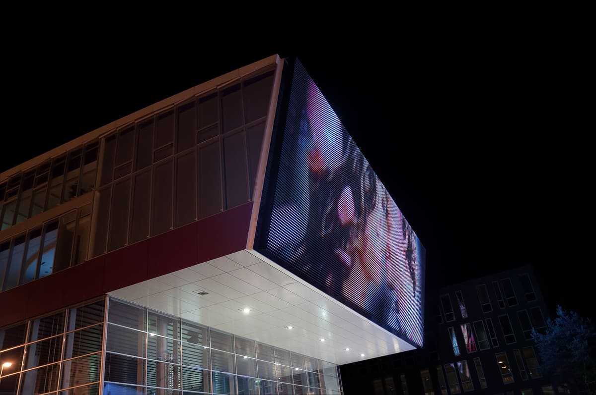 Large outdoor LED display wrapping the corner of a modern building at night